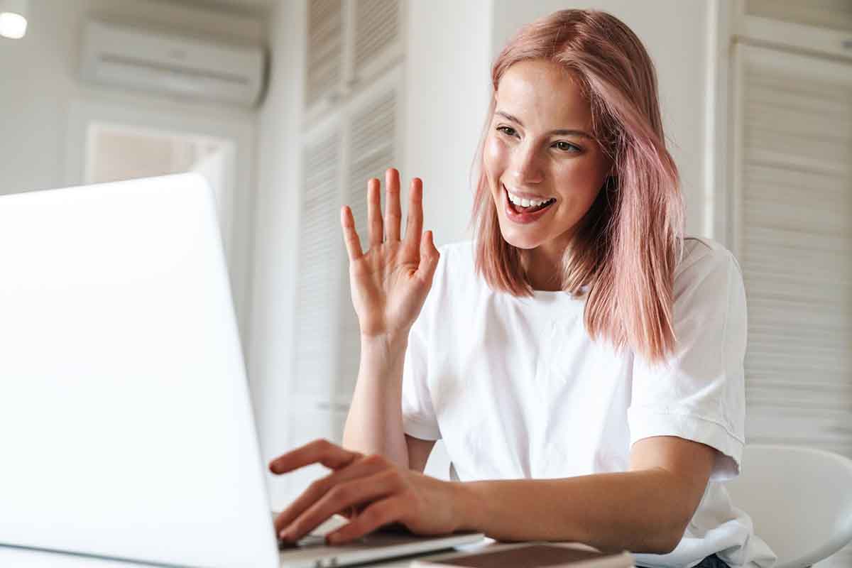 YOUNG GIRL WAVING AT VIRTUAL SESSION ON LAPTOP