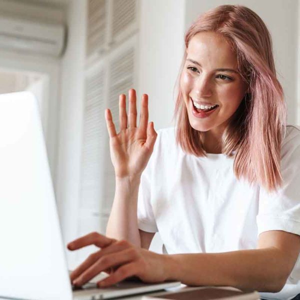 YOUNG GIRL WAVING AT VIRTUAL SESSION ON LAPTOP